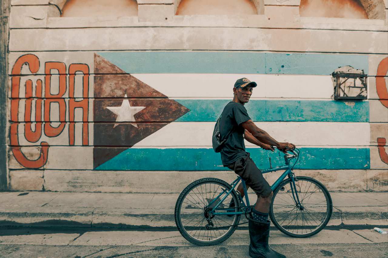 man with a bike parked beside a wall painting